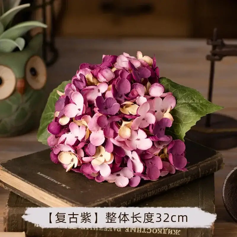 A cluster of decorbites artificial hydrangea silk flowers in purple and pink with green leaves for wedding decor