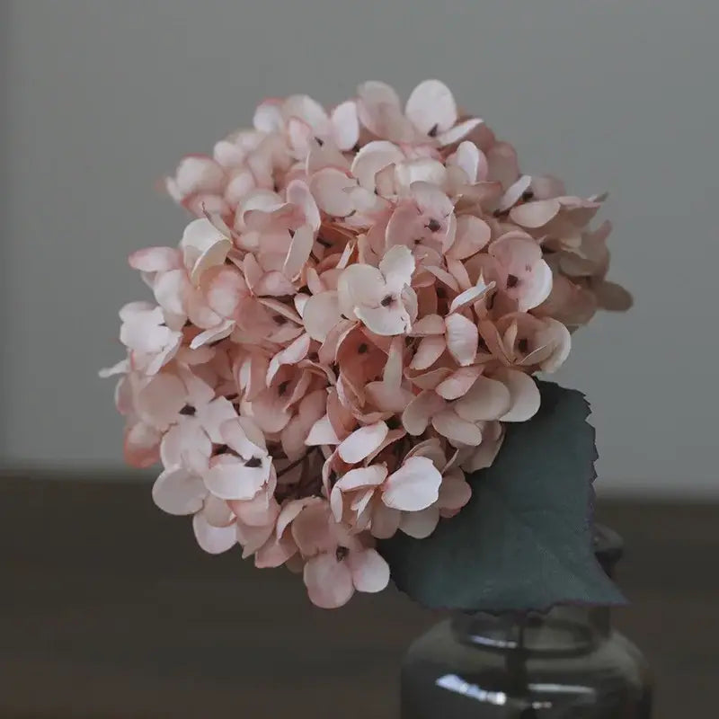 A delicate cluster of soft pink and white decorbites artificial hydrangea silk flowers with a dark green leaf