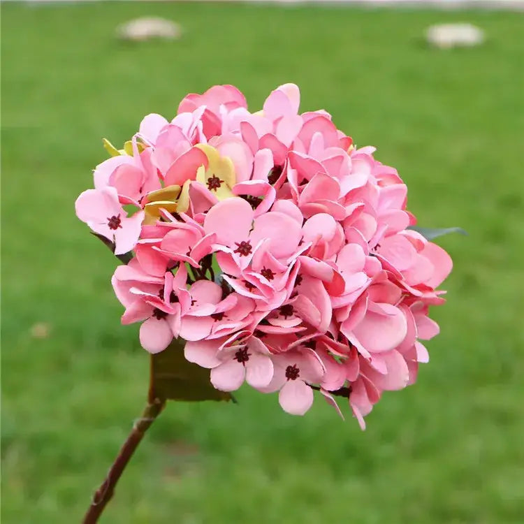 A cluster of artificial pink hydrangea wedding flowers with yellow accents in a dense indoor bonsai bouquet decor