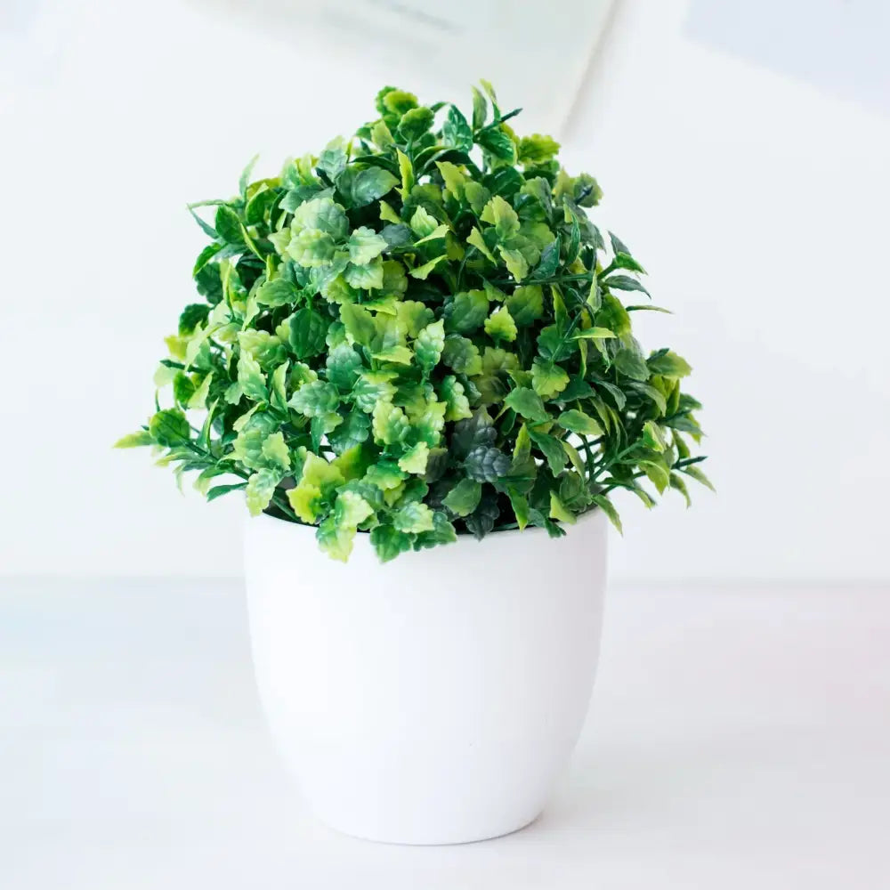 A decorbites artificial mini plant bonsai with lush varied green leaves in a white ceramic pot for desktop decor