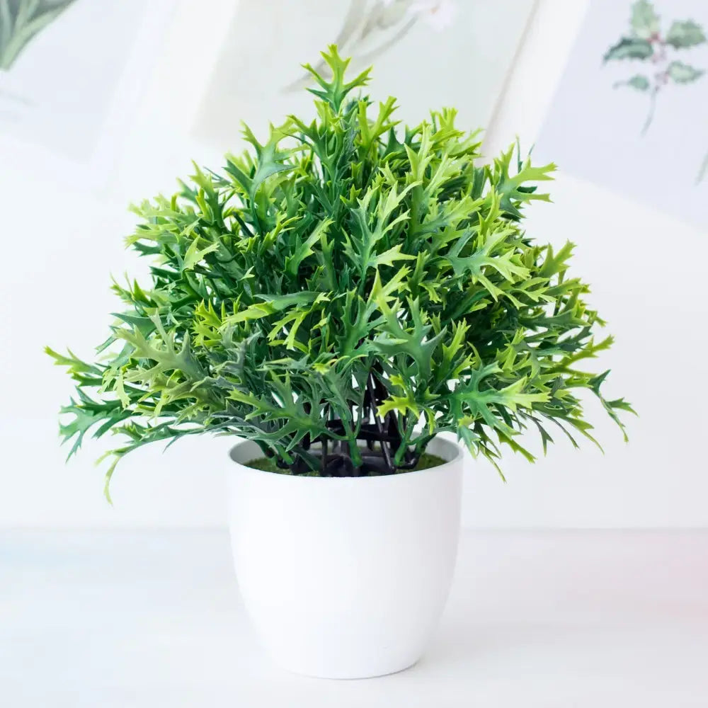 A decorbites artificial mini green plant bonsai with serrated leaves in a white ceramic pot for desktop decor