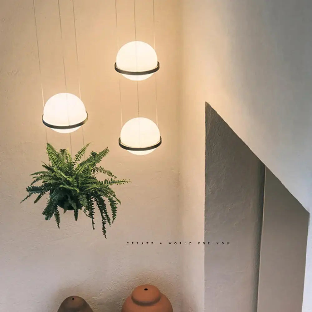 Three frosted glass spherical pendant lights with black metal rims in decorbites artificial plant pendant light