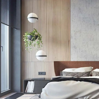 Two spherical white pendant lights with black horizontal bands featured in DecorBites artificial plant pendant light design
