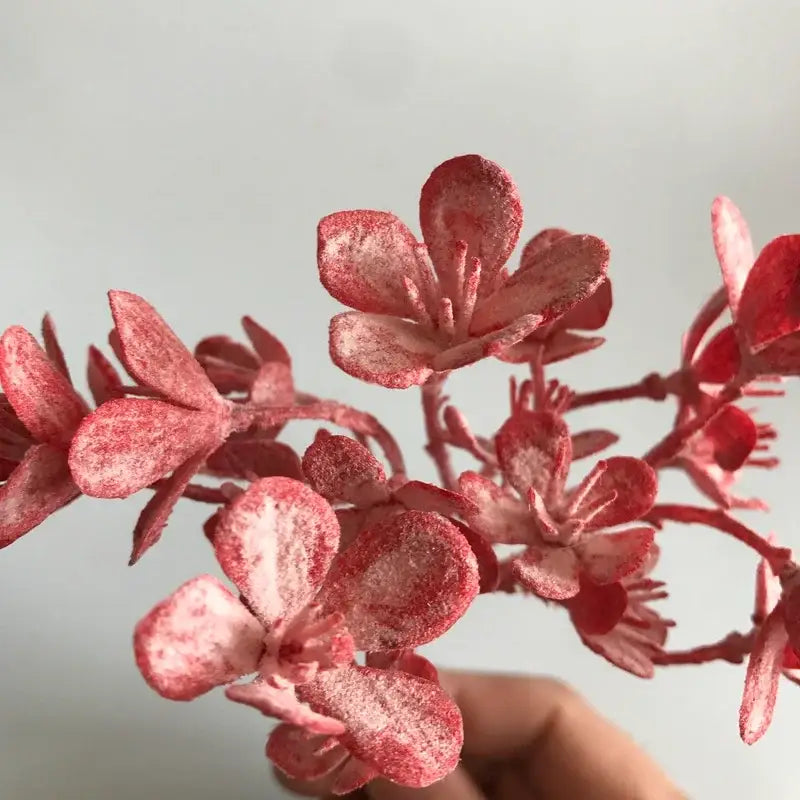 A delicate branch of artificial pink blossoms with frosted texture from DecorBites artificial plants for home decor