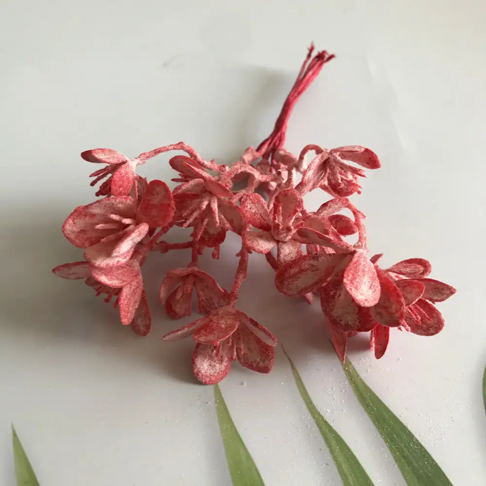 A cluster of red artificial flowers with textured petals in decorbites artificial plants for wedding home decor