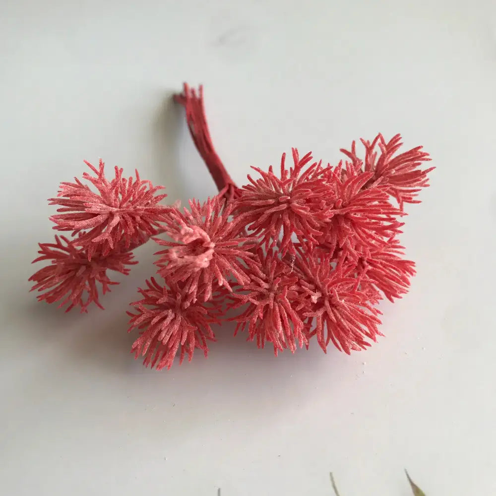 A cluster of artificial coral red spiky foliage with textured fibrous appearance from decorbites artificial plants set