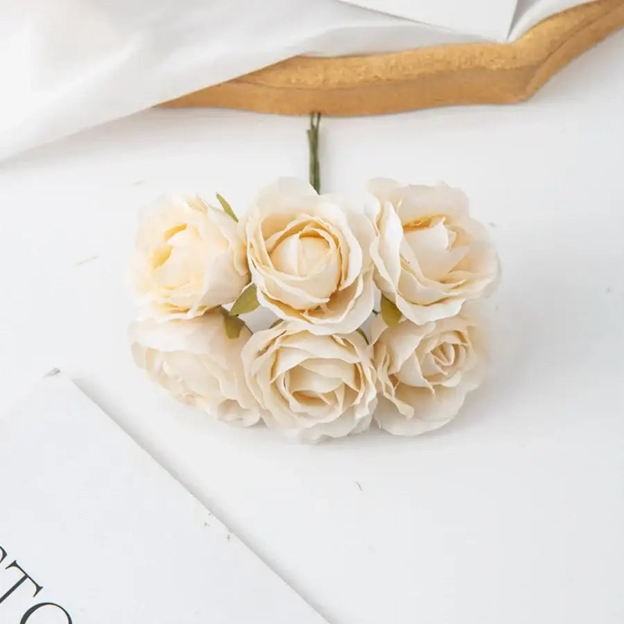A cluster of five cream-colored decorbites artificial rose bouquet with delicate petals and green stems for home decor