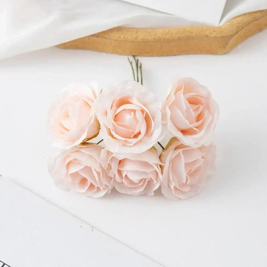 A delicate cluster of six blush pink decorbites artificial roses with soft petals in an artificial rose bouquet
