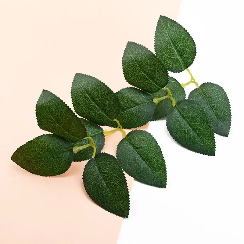 A cluster of decorative silk greenery rose leaves with detailed veining on a light yellow stem for greenery wreaths