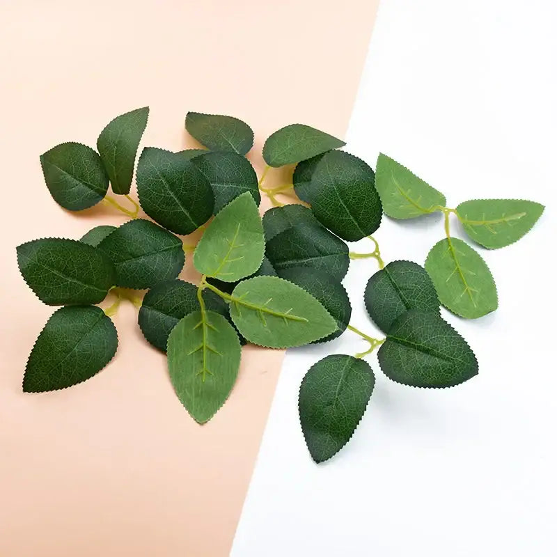 A cluster of silk greenery wreaths featuring artificial green rose leaves with detailed veining and a soft matte finish