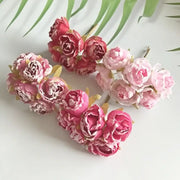 A cluster of decorbites artificial roses in pink and deep red fabric with glittery accents for bridal decoration