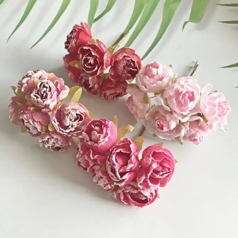 A cluster of decorbites artificial roses in pink and deep red fabric with glittery accents for bridal decoration