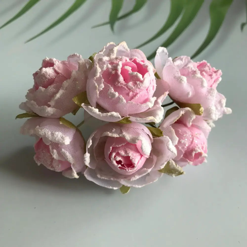 A cluster of delicate pink fabric artificial roses with white lace trim and green stems in decorbites artificial roses bridal bouquet