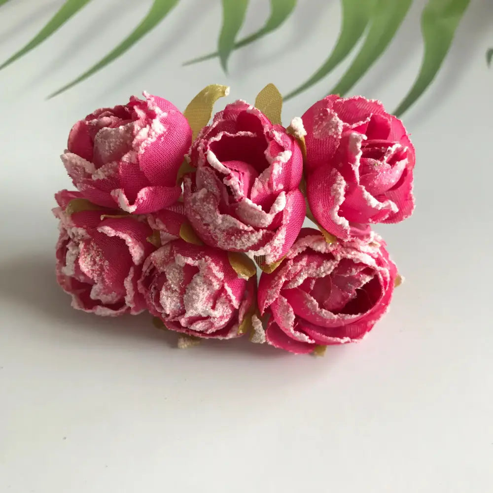 A cluster of five vibrant pink decorbites artificial roses with white sugar-edged petals for bridal decoration