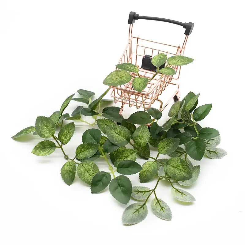 A delicate green artificial leaf garland with realistic veining alongside a rose gold miniature cart for decorbites artificial roses wreath silk flowers decor
