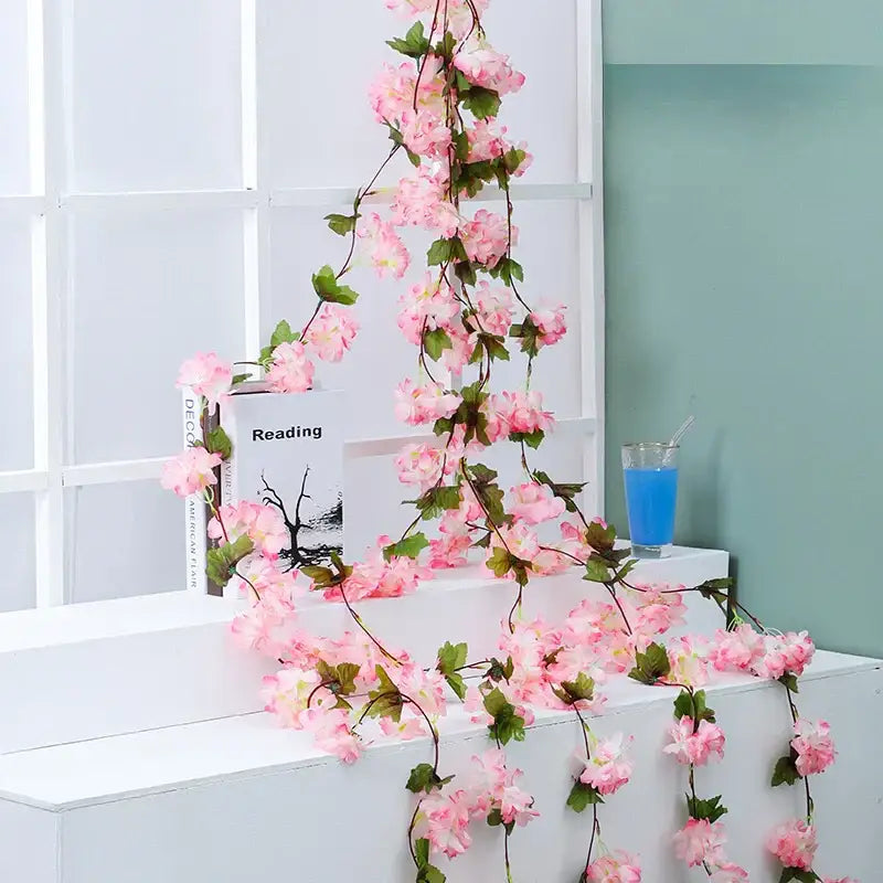 A delicate pink decorbites artificial sakura vine with green leaves and slender stems for wedding garden decoration