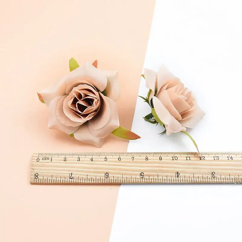 Two delicate blush pink decorbites artificial silk roses with green stems displayed beside a wooden ruler for scale