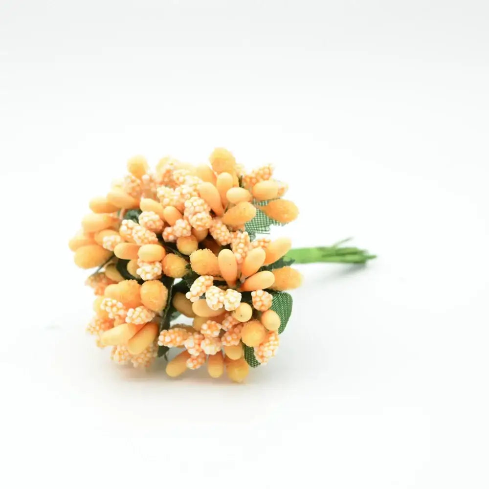 A delicate cluster of orange and cream decorbites artificial stamen flowers with green fabric leaves in a compact bouquet
