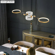 Modern gold and white geometric metal light fixture with circular rings and black accent for dining room gold ring island
