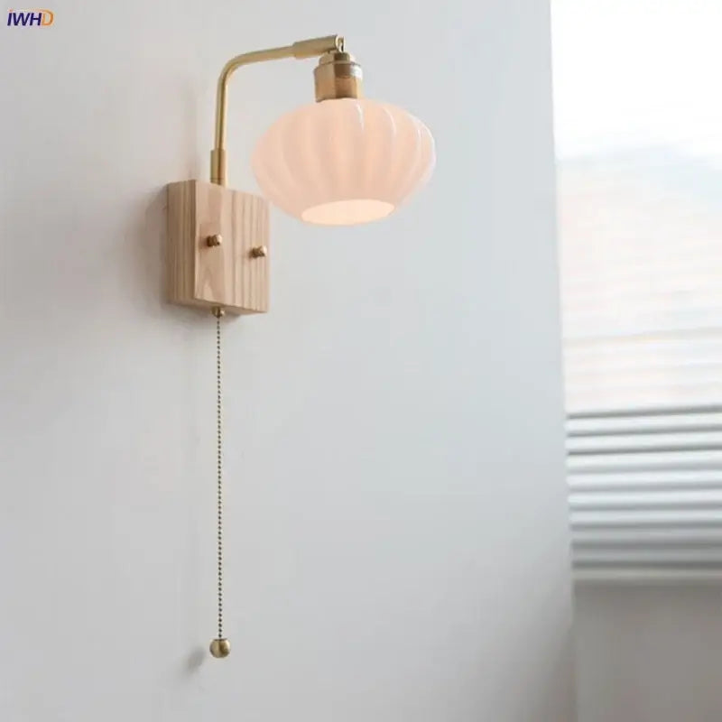 A warm-toned brass wall light with ash wood base and off-white ribbed glass shade from DecorBites ash wood collection