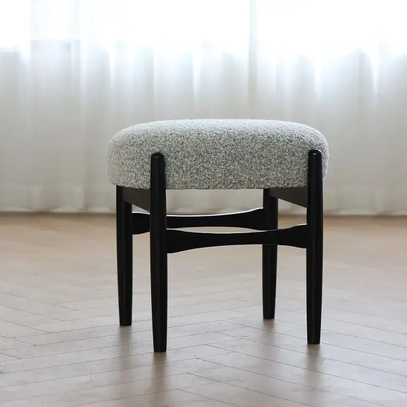 A sleek black ash wood makeup bench with a round gray upholstered seat by decorbites for small spaces