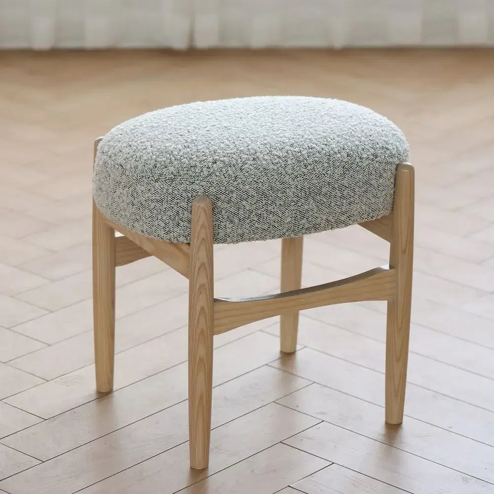 A light gray textured cushioned makeup bench with ash wood slender legs from DecorBites ash wood collection