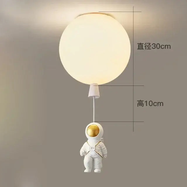 Decorbites astronaut balloon ceiling lamp featuring a white figurine with gold accents on a frosted glass light fixture
