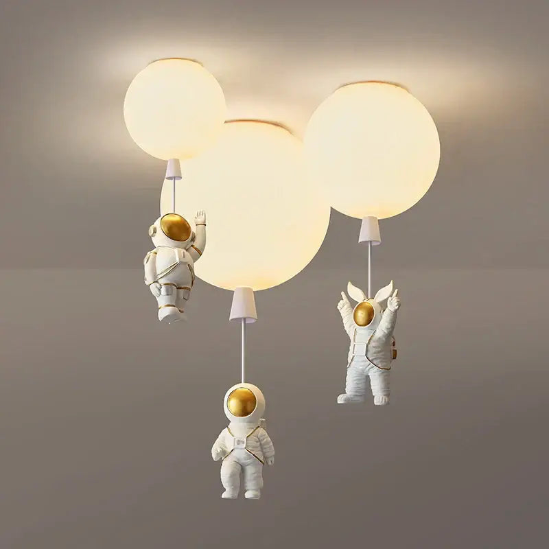 White decorbites astronaut balloon pendant light featuring golden helmets and softly glowing spherical bulbs for nursery rooms
