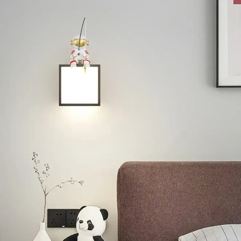 White and gold DecorBites astronaut cartoon metal sconce with square black-framed light for living room décor