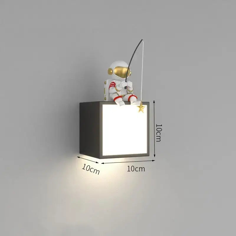 White metal decorbites astronaut cartoon sconce with gold visor and red-striped suit holding fishing rod on cube lamp