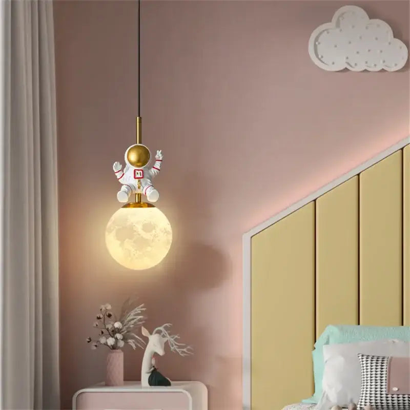 DecorBites astronaut chandelier features a white and gold astronaut pendant above a glowing textured moon globe for children