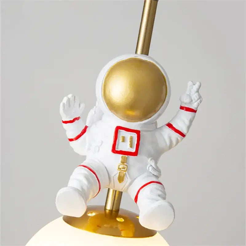 Decorbites astronaut chandelier featuring white lamp with gold helmet and red accents for children’s room lighting