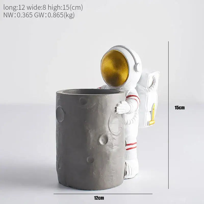 Decorbites astronaut pen holder figurine in white with gold visor and red stripes holding a gray moon-themed container