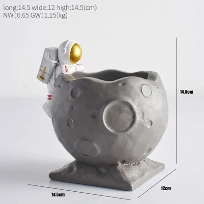 Gray resin moon-shaped pen holder with white astronaut figurine featuring gold visor and backpack details for desk use