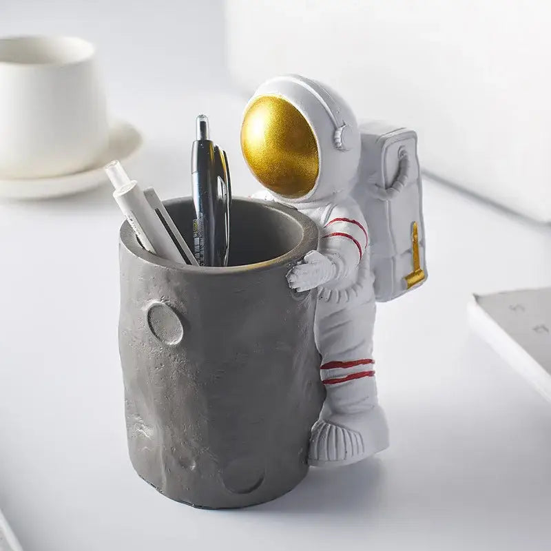 Decorbites™ gray textured moon-shaped pen holder figurines with astronaut featuring gold helmet and red suit stripes