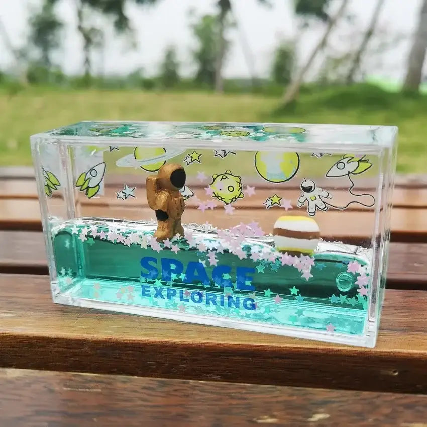 Clear acrylic decorbites astronaut drift keychain with golden astronaut, floating planets, teal liquid, and pink stars inside