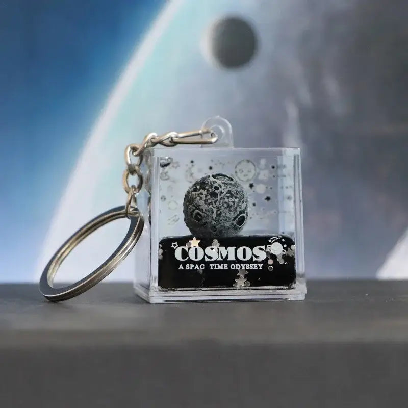 Clear acrylic decorbites astronaut drift keychain with black silver textured moon and cosmos label in resin design