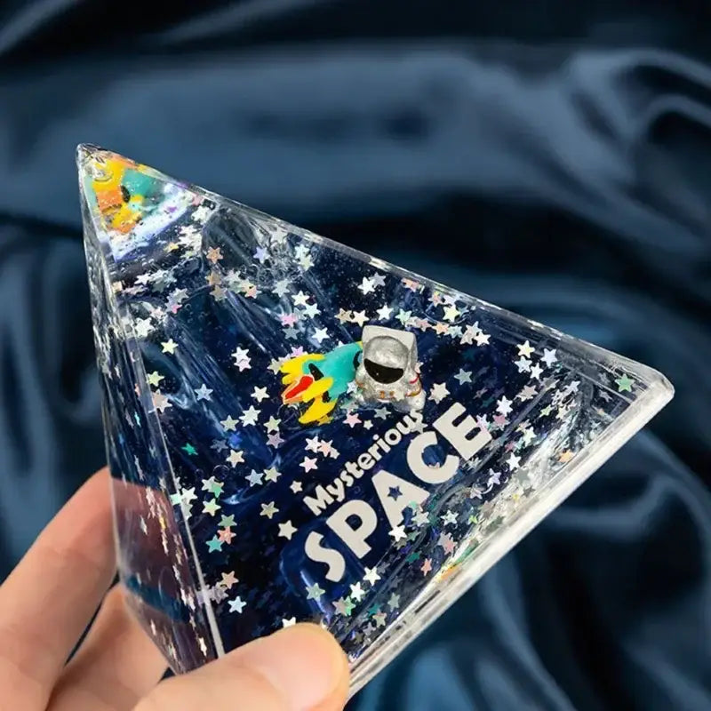 Clear triangular liquid-filled DecorBites astronaut drift keychain with miniature astronaut colorful rocket and glittering stars