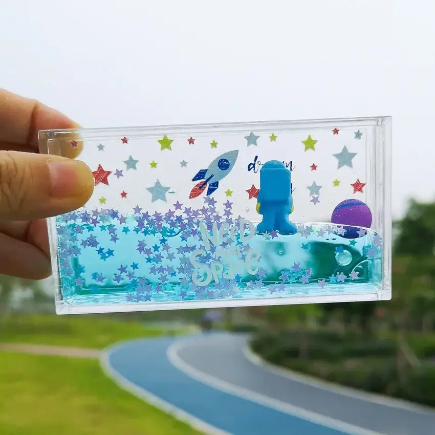 Clear rectangular resin keepsake box with blue astronaut, rocket, and purple planet star glitter in decorbites astronaut drift keychain