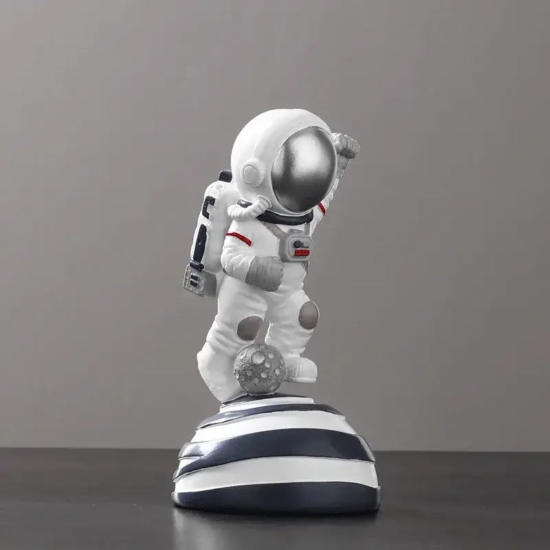 Decorbites astronaut figurine abstract sculpture featuring a white body with silver helmet and red accents on striped base