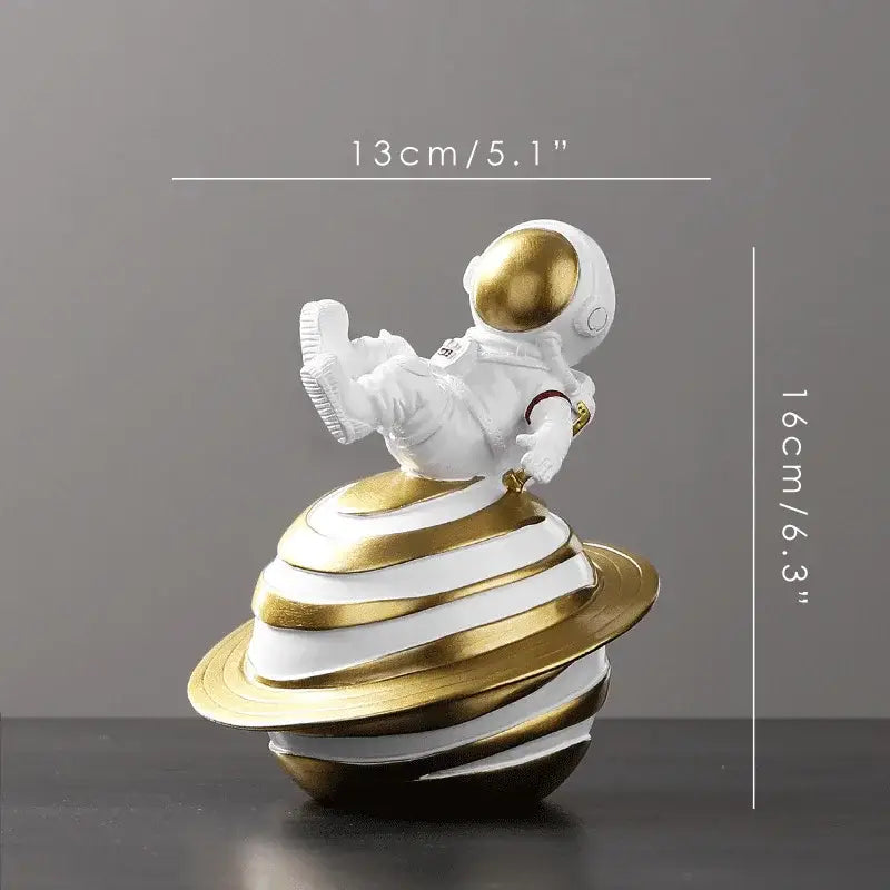 Decorbites astronaut figurine abstract sculpture in white with gold accents sitting on a striped gold and white planet base