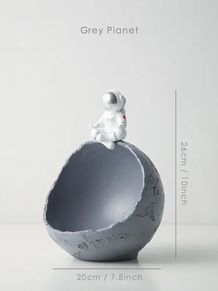 Decorbites astronaut figurine abstract sculpture in white sits atop a textured grey planet-shaped bowl for modern decor