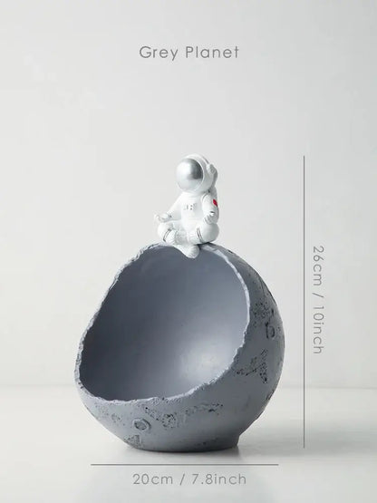 Decorbites astronaut figurine abstract sculpture in white sits atop a textured grey planet-shaped bowl for modern decor