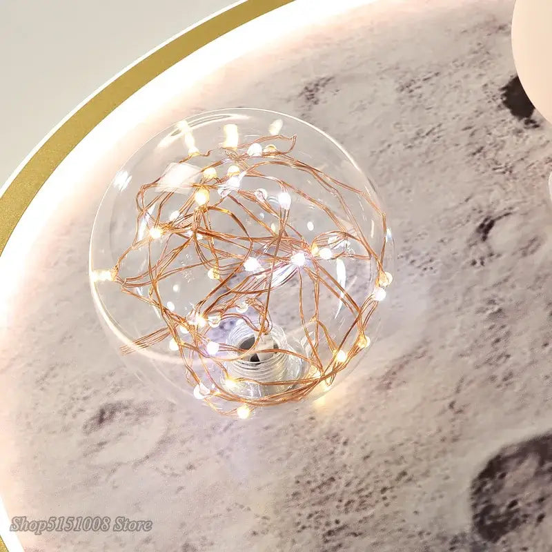 A clear glass globe filled with glowing copper wire fairy lights in decorbites astronaut led ceiling light