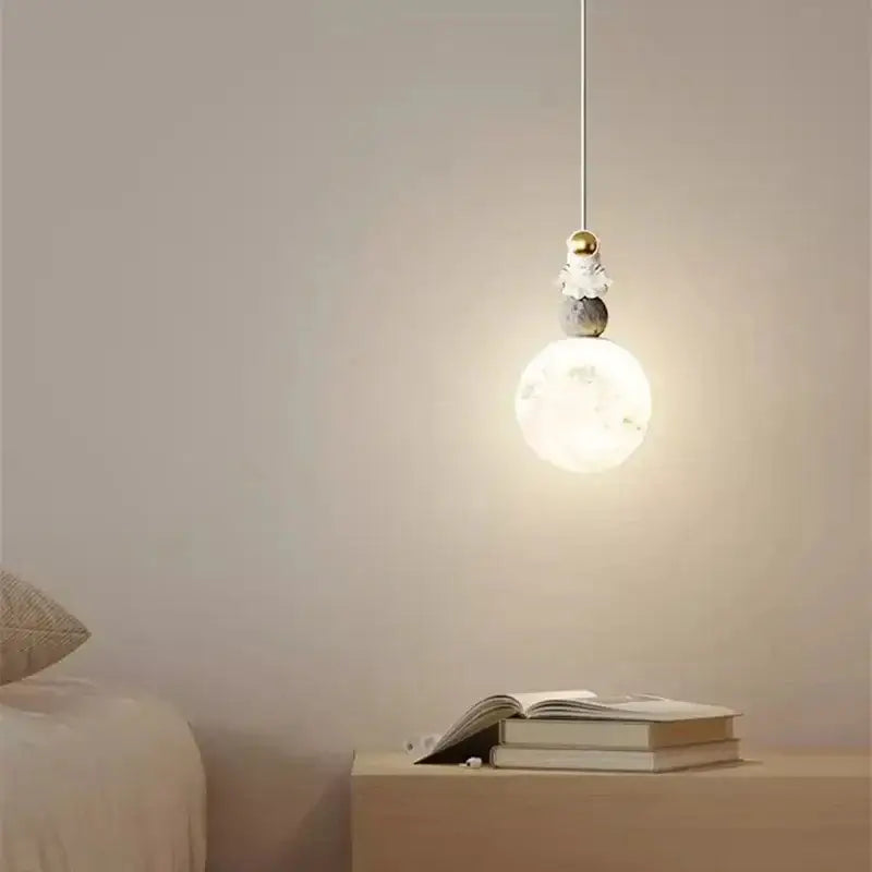 Minimalist pendant light with glowing bulb and golden astronaut figurine on gray stone by decorbites astronaut lunar