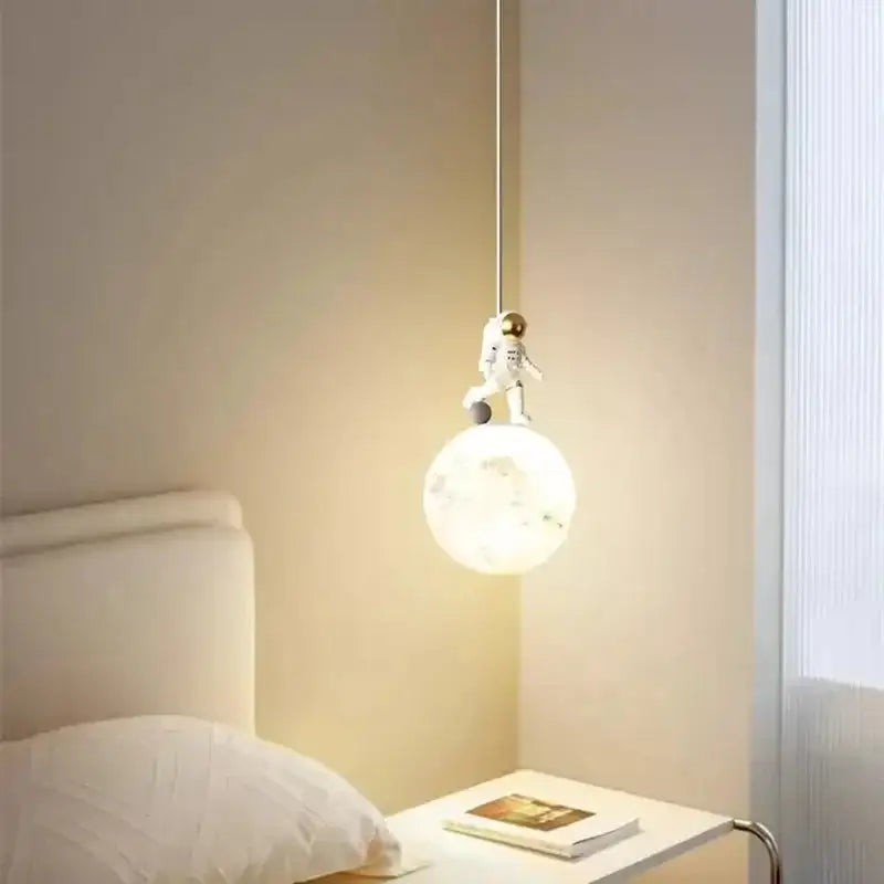 A white astronaut figurine perched on a glowing translucent spherical lampshade in decorbites astronaut lunar pendant light