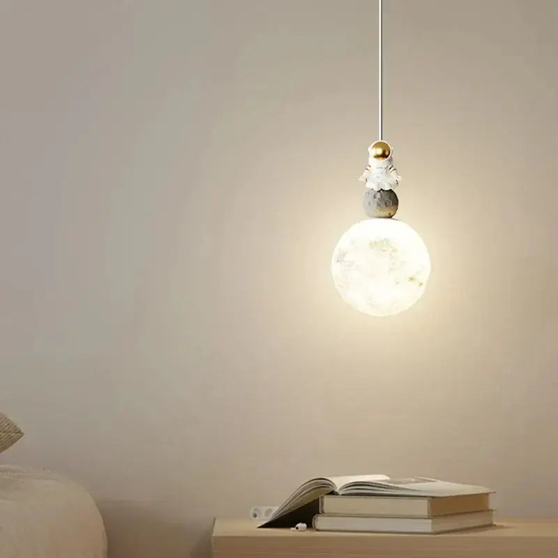 A delicate white and gold decorbites astronaut lunar pendant light features a translucent moon-shaped fixture for modern decor