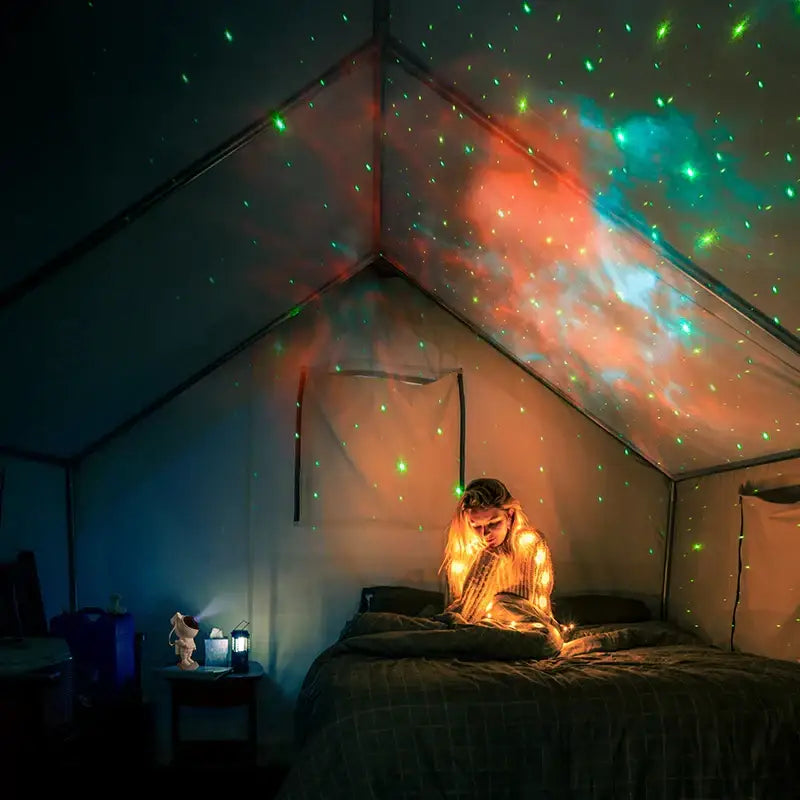 Decorbites astronaut projector starry night light casting green and red cosmic patterns as a night light in a tent