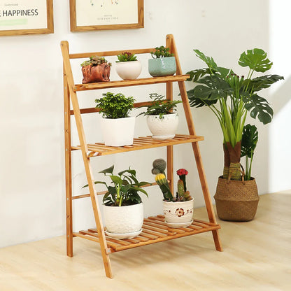 DecorBites™ bamboo 3 tier light brown wooden folding shelf stand holding potted plants in white and patterned pots