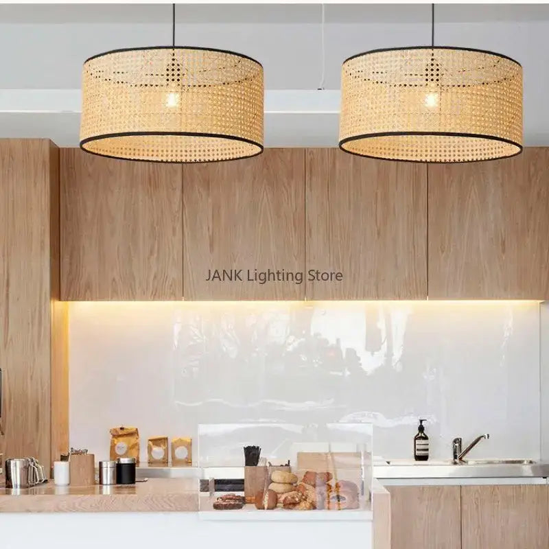Two cylindrical decorbites bamboo core rattan pendant lights with black trim hang above a modern kitchen counter